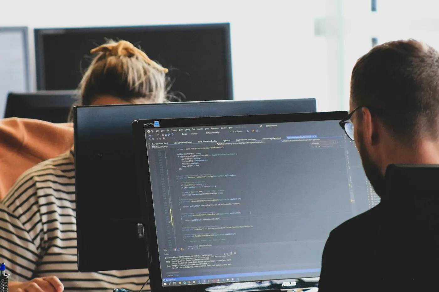 Two developers coding at monitors in a workspace